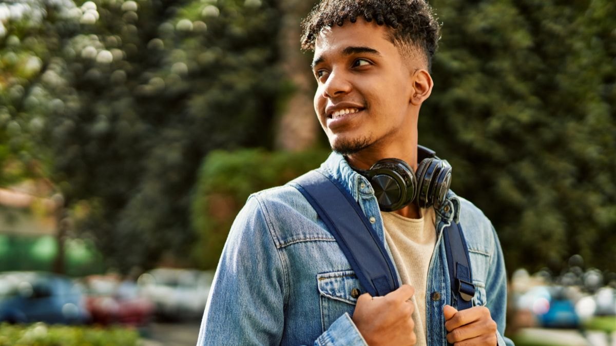 Estudante com fones de ouvido e mochila ao ar livre