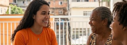 Estudante mostrando um tablet a duas moradoras durante ação comunitária
