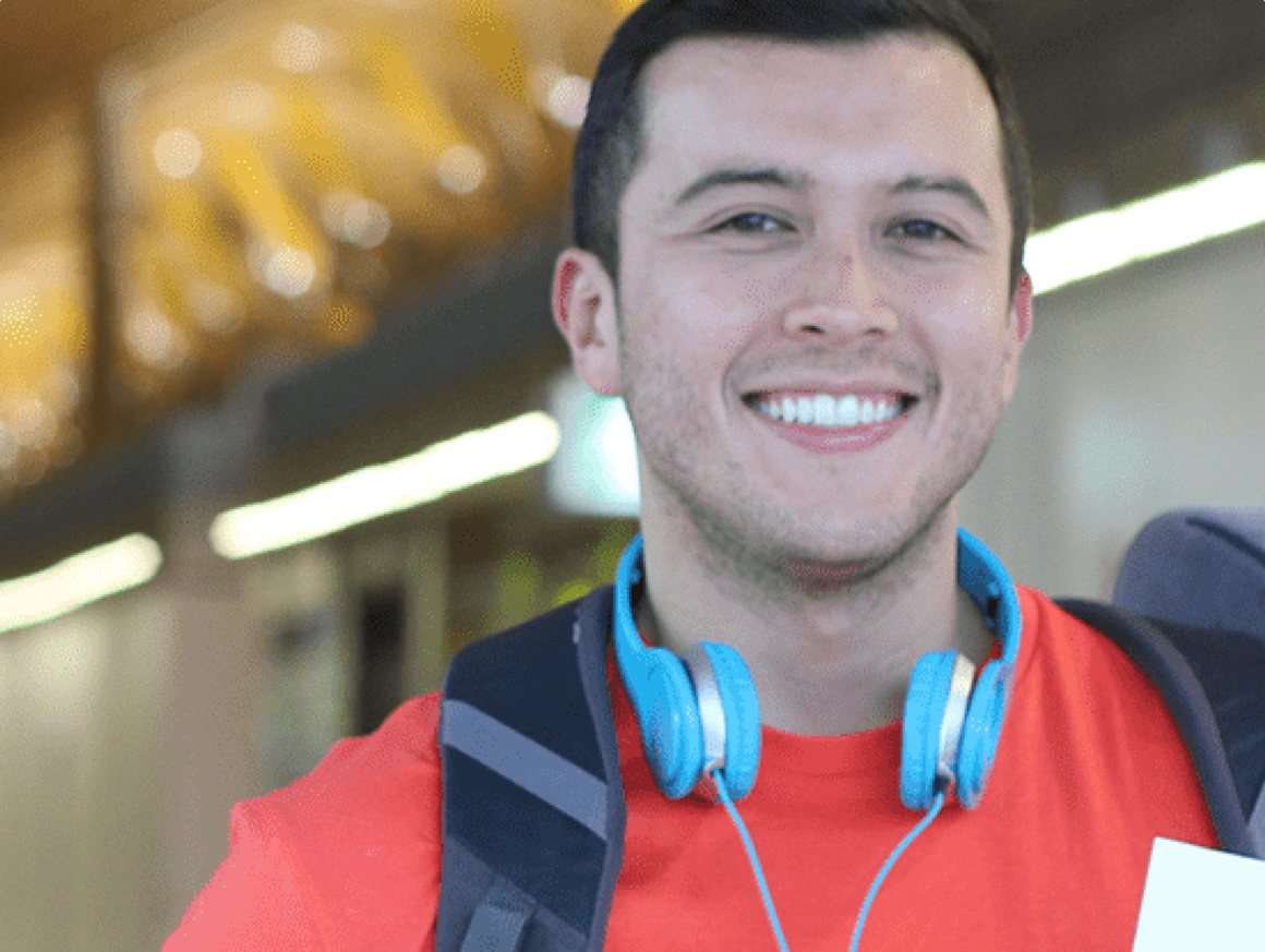 Estudante sorrindo com fones de ouvido azuis e mochila nas costas