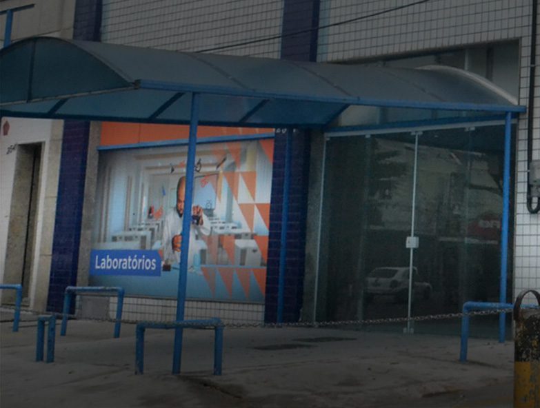 Entrada da unidade Campo Grande, com cobertura azul e o painel "Laboratórios"