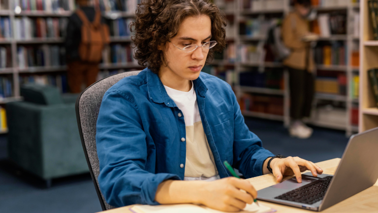 rapaz estudando na biblioteca da universidade