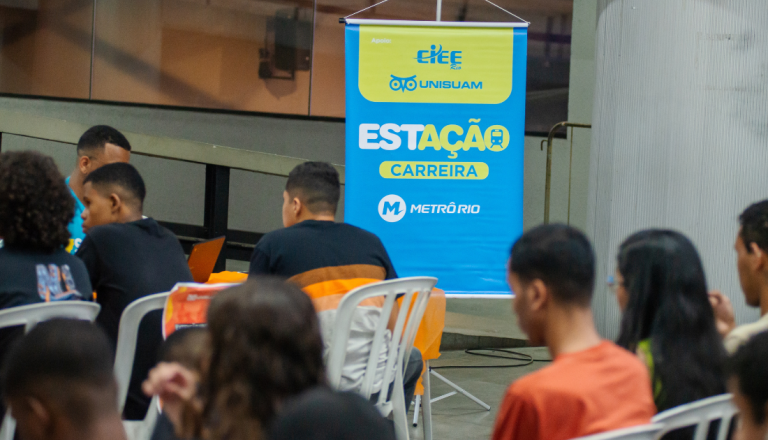 Participantes reunidos em ação do projeto Estação Carreira, com banner da iniciativa em parceria entre UNISUAM, CIEE Rio e MetrôRio.