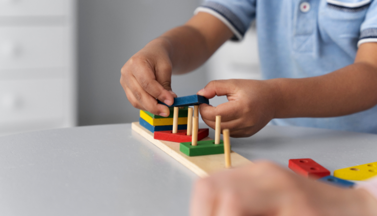 Criança manipula brinquedo educativo de madeira com peças coloridas durante atividade de coordenação motora.