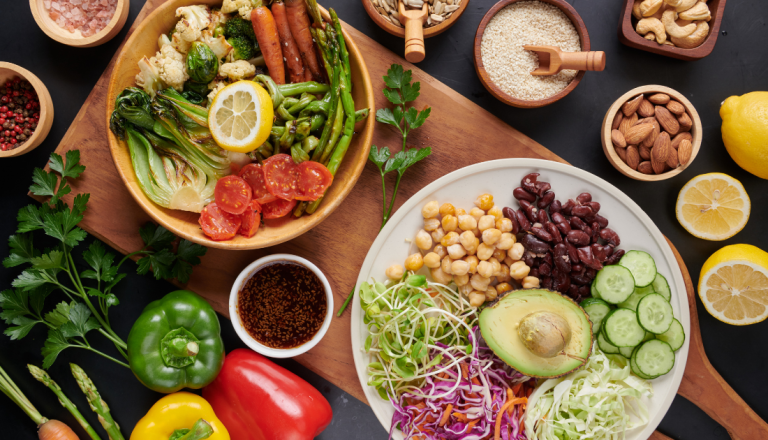Mesa com pratos coloridos de alimentação saudável, contendo legumes, verduras, grãos, sementes e oleaginosas.