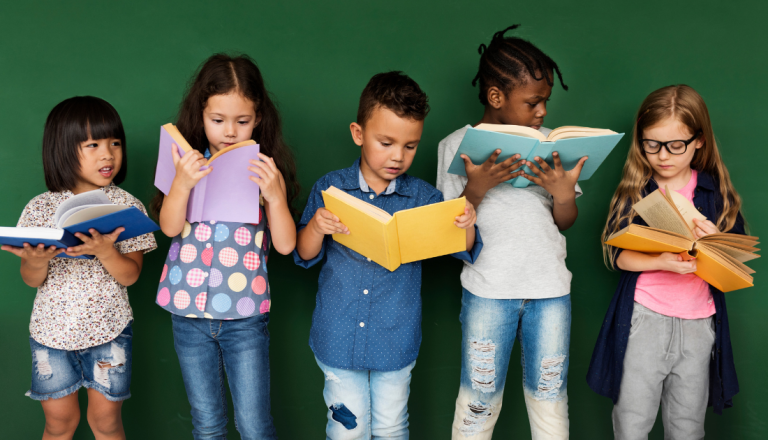 Cinco crianças de diferentes etnias leem livros coloridos lado a lado, representando o incentivo à leitura, à diversidade e ao desenvolvimento cultural na infância.