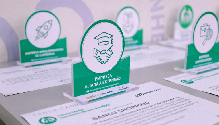 Troféus e certificados de reconhecimento em responsabilidade social organizados sobre uma mesa durante uma cerimônia de premiação.