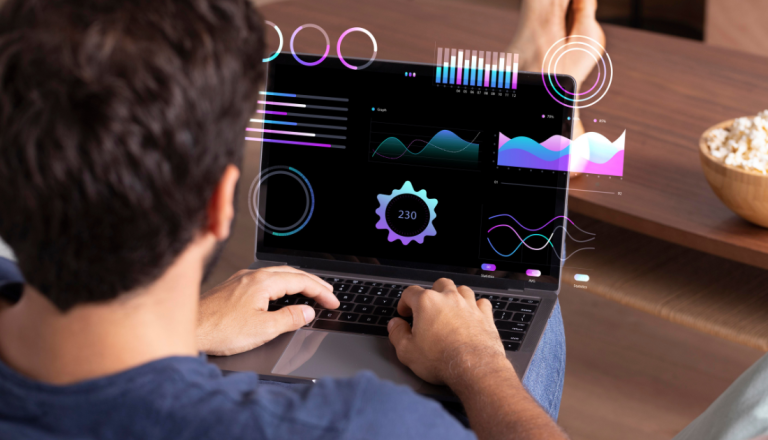 Pessoa utiliza um notebook com painéis de gráficos e indicadores digitais, representando análise de dados e desenvolvimento de sistemas.